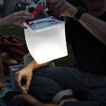 Hands holding up a solar lantern that is lighting up the night